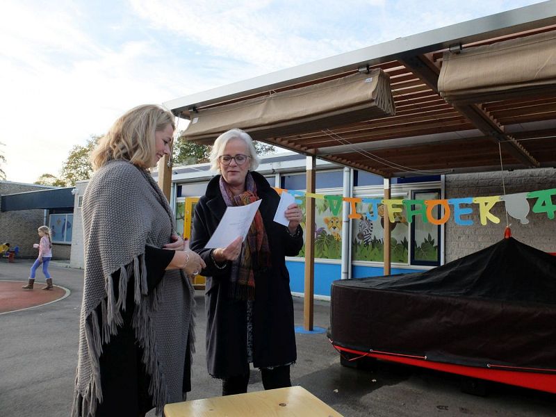 Teamleider Angelique Besseling van De Waerden (links) ontvangt een juibileumcadeau namens de gemeente Heiloo van wethouder jeugdzorg Elly Beens (rechts).