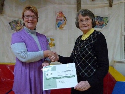 mevrouw Rietje Terol, voorzitter van De Stichting Vrienden van het Ouderenwerk Heiloo, een cheque van € 500,- aan Janny Fernee, bureausecretaresse van De Vijfhoek. 